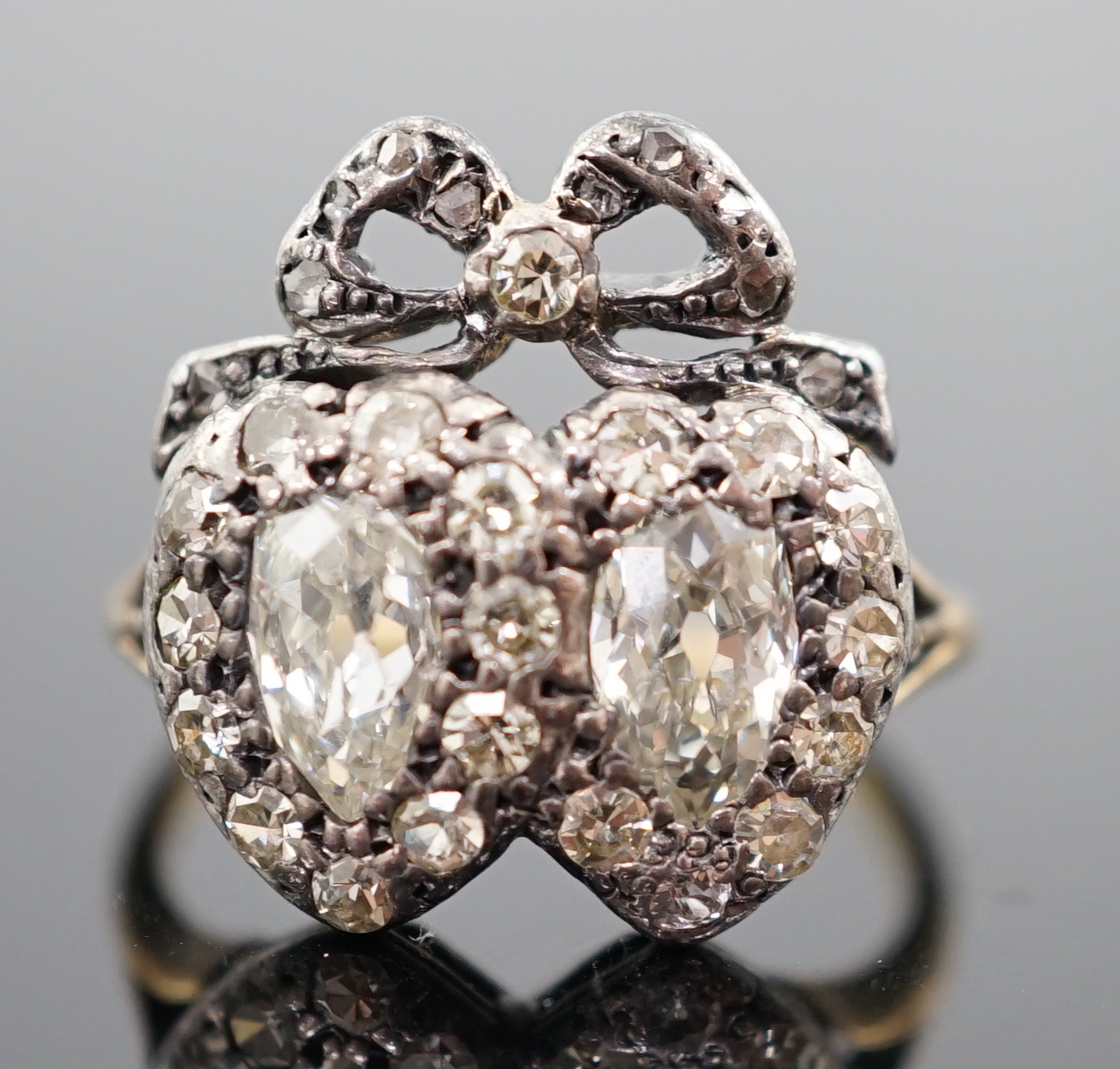 A 19th century gold, silver and diamond cluster set twin hearts ring, with ribbon bow surmounted